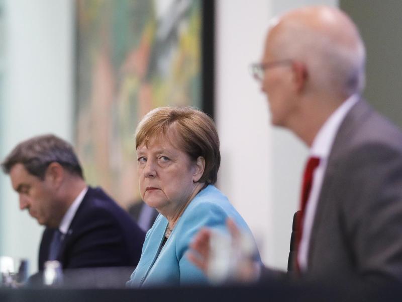 Bundeskanzlerin Angela Merkel nimmt zusammen mit dem bayerischen Ministerpräsident Markus Söder und Hamburgs Erstem Bürgermeister Peter Tschentscher nach Abschluss der Beratungen an einer Pressekonferenz teil. Foto: Markus Schreiber/AP-Pool/dpa