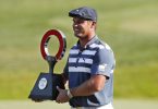 Bryson DeChambeau hält die Trophäe des Golfturniers Rocket Mortgage Classic in den Händen. Foto: Carlos Osorio/AP/dpa