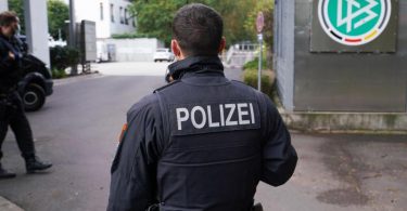 Ein Polizist steht vor der DFB-Zentrale in Frankfurt/Main. Wegen des Verdachts der Steuerhinterziehung wurden die Geschäftsräume des DFB durchsucht. Foto: Frank Rumpenhorst/dpa