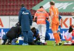 Ein Notarzt kümmert sich um Mark Uth. Die Verletzung des Schalke-Stürmers hat die Partie in Augsburg überschattet. Foto: Stefan Puchner/dpa