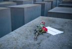 Rosen liegen mit einem Zettel mit der Aufschrift '#weremember' am Holocaust-Mahnmal in Berlin. Foto: Dorothee Barth/dpa