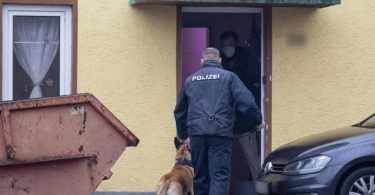 Razzia gegen Neonazi-Netzwerk: Ein Polizist mit einem Drogenspürhund geht in ein Haus in Thüringen. Foto: Michael Reichel/dpa-Zentralbild/dpa