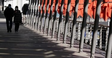 Passanten gehen an dem geschlossenen Außenbereich eines Cafés an den Alsterarkaden in der Hamburger Innenstadt vorbei. Foto: Marcus Brandt/dpa