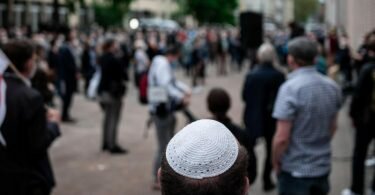 Menschen stehen bei einer Solidaritätskundgebung in&nbsp;Gelsenkirchen auf dem Platz vor der Synagoge. Dabei trägt ein Mann eine Kippa. Foto: Fabian Strauch/dpa