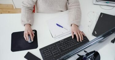Eine Frau arbeitet in ihrer Wohnung vor einem Computer an einem Stehtisch. (Symbolbild). Foto: Uwe Anspach/dpa