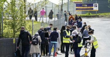 Menschen warten in einer Schlange vor dem mobilen Covid-Impfzentrum an der ESSA-Akademie in Bolton. Foto: Danny Lawson/PA Wire/dpa