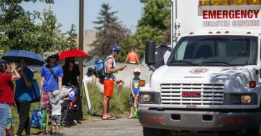 Ein Rettungswagen der Heilsarmee dient als Kühlstation, während die Menschen Schlange stehen, um in einen Wasserpark zu gelangen. Foto: Jeff Mcintosh/The Canadian Press via ZUMA/dpa