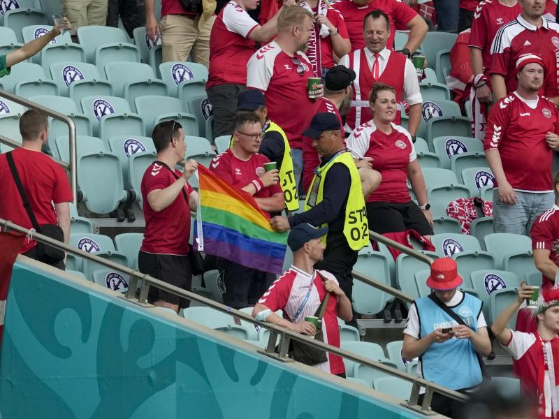 Ordner nehmen zwei Dänemark Fans eine Regenbogen-Fahne ab. Foto: Darko Vojinovic/Pool AP/dpa