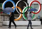 Passanten gehen an Olympischen Ringen in Tokio vorbei. Während der Spiele wird es keine Fans in den Stadien geben. Foto: Rodrigo Reyes Marin/ZUMA Wire/dpa