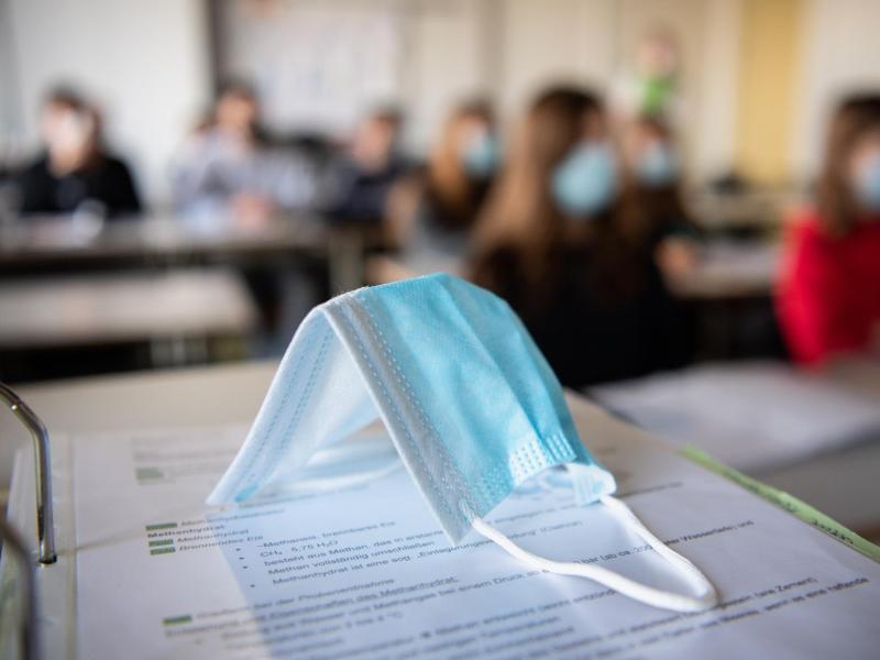Eine Maske liegt auf einem Tisch in einer Münchner Schule. Foto: Matthias Balk/dpa