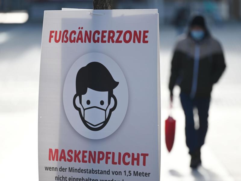 Ein Schild weist auf die Maskenpflicht in der Fußgängerzone hin. Foto: Marijan Murat/dpa