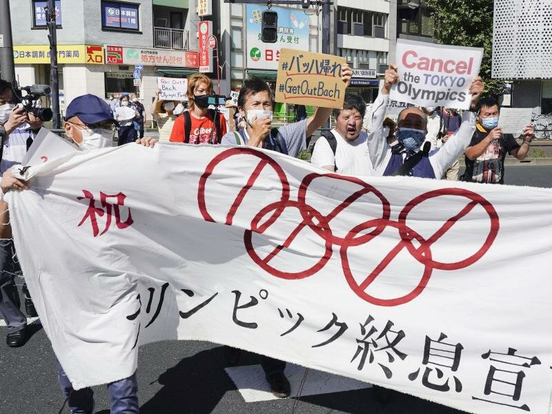 Demonstranten marschieren mit einem Banner und Plakaten bei einem Protest gegen die Olympischen und Paralympischen Sommerspiele. Foto: Koji Harada/Kyodo News/AP/dpa