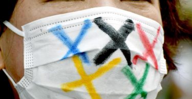 Eine Frau trägt einen Mund-Nasen-Schutz mit den fünf Farben der fünf olympischen Ringe während der Ankunft der olympischen Fackel in Tokio. Foto: Ramiro Agustin Vargas Tabares/ZUMA Press Wire/dpa
