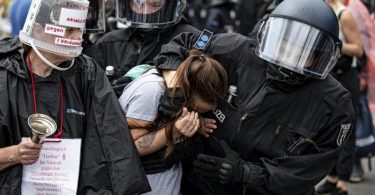 Polizisten nehmen an der Siegessäule eine Demonstrantin fest. Foto: Fabian Sommer/dpa