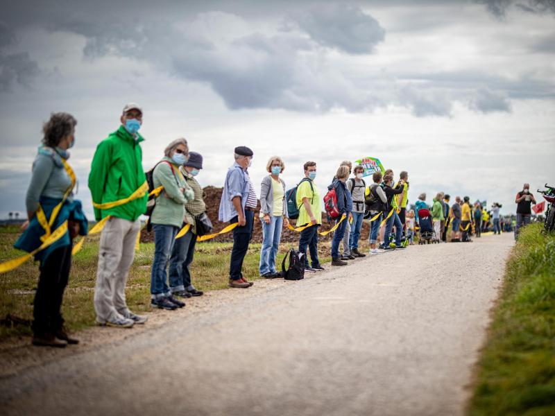 Umwelt- und Klimaschützer sowie Bewohner der angrenzenden Dörfer bilden am Rande des Braunkohletagebaus Garzweiler eine Menschenkette. Foto: Malte Krudewig/dpa