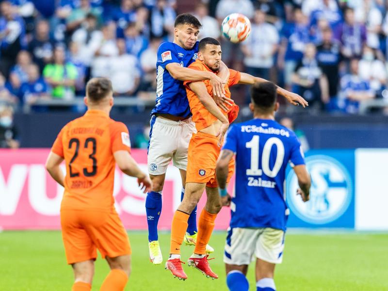 Schalkes Mehmet Aydin (2.v.l.) und Aues Soufiane Messequem (2.v.r.) gehen zum Kopfballduell hoch. Foto: Marcel Kusch/dpa