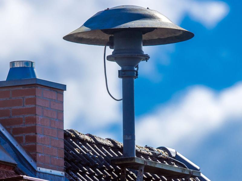 Eine Alarmsirene auf einem Hausdach. Foto: Jens Büttner/dpa-Zentralbild/dpa