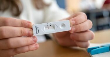 Ein Schülerin zeigt in einer Klasse ihren negativen Corona-Schnelltest. Foto: Sebastian Gollnow/dpa