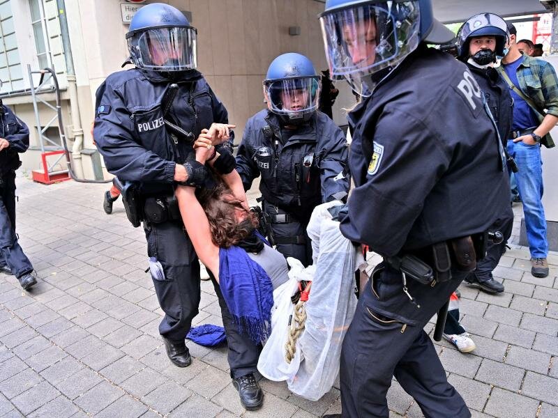Eine Protestteilnehmerin wird von Polizisten weggetragen. Foto: Peter Kneffel/dpa