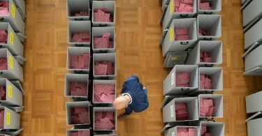 Markus Blocher, Kreiswahlleiter, begutachtet in einer Wahlbehörde zahlreiche Wahlurnen gefüllt mit Stimmzettelumschlägen für die Briefwahl. Foto: Sebastian Kahnert/dpa-Zentralbild/dpa