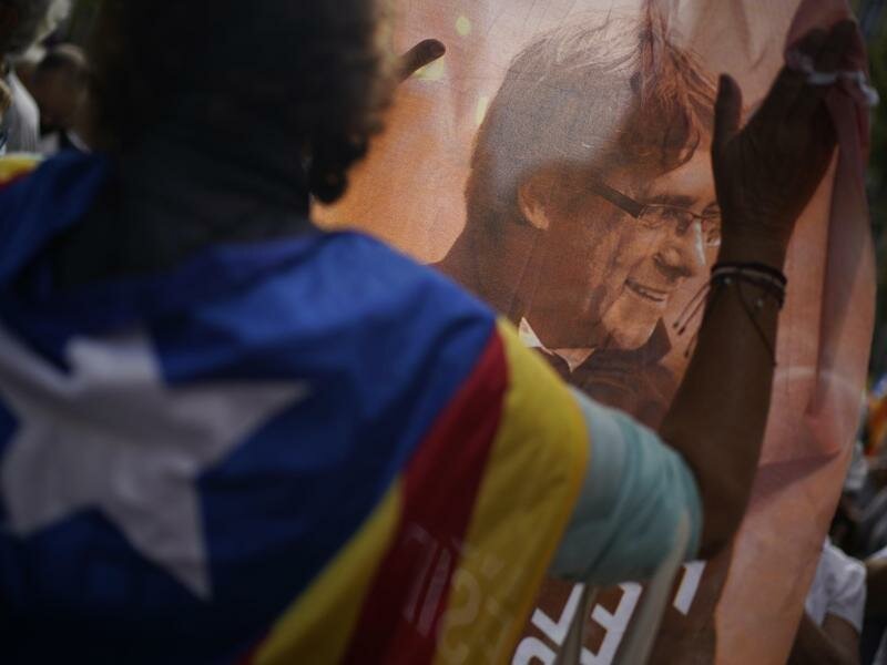 Ein Mann hält ein bedrucktes Tuch mit dem Bild des ehemaligen katalanischen Regierungschefs Puigdemont während eines Protests vor dem italienischen Konsulat in Barcelona. Foto: Joan Mateu/AP/dpa