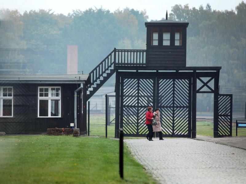 Besucher gehen am Eingang des Stutthof Museums in Sztutowo (Polen) vorbei, in dem an die Verbrechen im ehemaligen deutschen Konzentrationslager Stutthof erinnert wird. Foto: Piotr Wittman/PAP/dpa