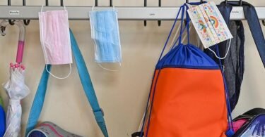 Masken hängen an Kleiderhaken in einer Grundschule. In der Debatte um eine Maskenpflicht an Schulen spricht sich der Präsident des Berufsverbands der Kinder- und Jugendärzte, Thomas Fischbach, gegen eine allgemeine Fortführung der Maßnahme aus. Foto: Patrick Pleul/dpa-Zentralbild/ZB