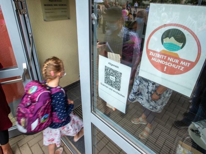 Ein Kind geht mit Maske in eine Schule. Das Robert Koch-Institut (RKI) registriert in einzelnen Regionen Deutschlands besonders viele Corona-Ansteckungen bei Kindern und Jugendlichen. Foto: Jens Büttner/dpa-Zentralbild/dpa