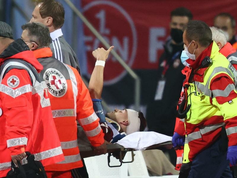 Der Nürnberger Tom Krauß (M) wird verletzt aus dem Stadion getragen, zeigt aber mit dem Daumen nach oben. Foto: Daniel Karmann/dpa