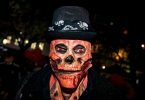 Ein Mann mit einer Totenkopf-Maske und glühenden roten Augen bei der Essener Halloween-Parade. Neben fantasievollen Kostümen gab es in der&nbsp;Nacht in Teilen Deutschlands auch Ruhestörungen, Böllerwürfe und Ausschreitungen. Foto: Malte Krudewig/dpa