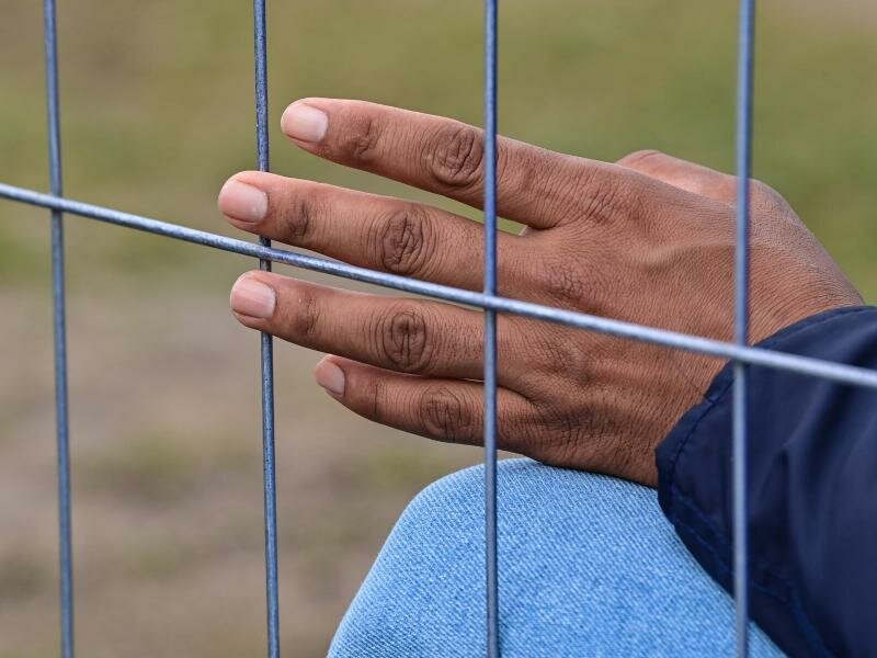 Die Hand eines Flüchtlings am Zaun einer Erstaufnahmeeinrichtung für Asylbewerber. Foto: Patrick Pleul/dpa-Zentralbild/ZB