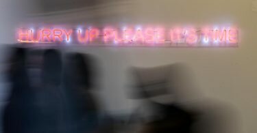 Konferenzteilnehmer gehen bei der UN-Klimakonferenz COP26 in Glasgow an einem Schriftzug der Künstlerin Cornelia Parker vorbei. Zu lesen ist «hurry up please it‘s time» (beeilt euch, es ist Zeit). Foto: Christoph Soeder/dpa