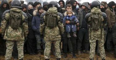 Migranten stehen an der belarussisch-polnischen Grenze vor belarussischen Soldaten. Foto: Oksana Manchuk/BelTA-Pool/AP/dpa