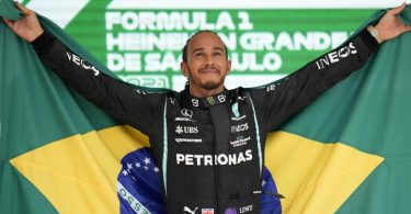 Grand-Prix-Sieger Lewis Hamilton steht mit einer brasilianischen Flagge auf dem Podium. Foto: Andre Penner/AP/dpa
