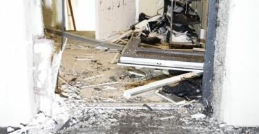 Scherben liegen in einem Gebäudeeingang, nachdem Einsatzkräfte bei einer Razzia die Tür aufgesprengt haben. Foto: Justin Brosch/dpa