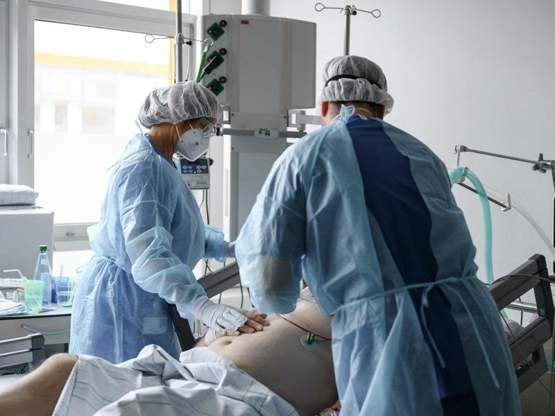 Die pflegerische Leitung der Intensivstation und Intensivstationsarzt bei einem Corona-Patienten auf der Intensivstation. (Archivbild). Foto: Daniel Vogl/dpa