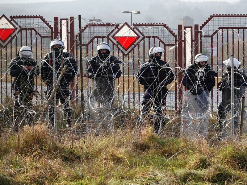 Polnische Sicherheitskräfte stehen an der Grenze hinter Stacheldraht. Foto: Ulf Mauder/dpa