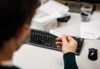 Ein Mitarbeiter blickt auf das Testergebnis für einen Corona-Schnelltest eines anderen Mitarbeiters. Foto: Matthias Balk/dpa
