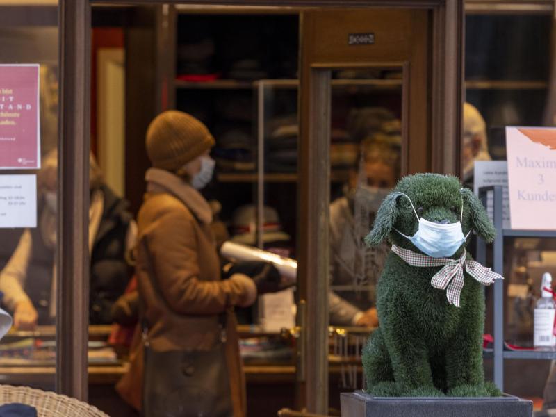 Vor einem Geschäft steht eine Hundefigur mit einer Maske. (Archivbild). Foto: Helmut Fricke/dpa