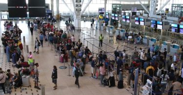 Reisende stehen am Flughafen in Kapstadt in langen Schlangen an den wenigen Schaltern an, die überhaupt noch offen sind. Foto: Kristin Palitza/dpa