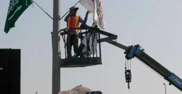 Ein Mitarbeiter hängt Flaggen an der Rennstrecke des Corniche Circuit auf: Die Formel 1 gastiert erstmals in Saudi-Arabien. Foto: Amr Nabil/AP/dpa