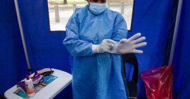 Ein Mitarbeiter des Gesundheitswesens bereitet sich darauf vor, eine Person in einer Einrichtung auf COVID-19 zu testen. Foto: Denis Farrell/AP/dpa