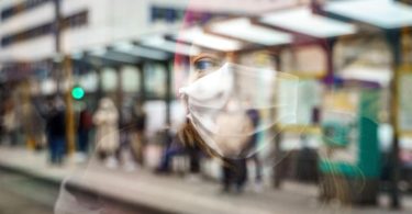 Ein weiblicher Fahrgast mit Mund-Nasen-Schutz spiegelt sich im Fenster einer Straßenbahn an der Konstablerwache in der Frankfurter Innenstadt. Foto: Frank Rumpenhorst/dpa