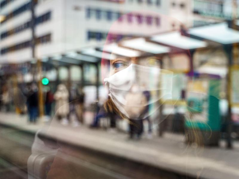 Ein weiblicher Fahrgast mit Mund-Nasen-Schutz spiegelt sich im Fenster einer Straßenbahn an der Konstablerwache in der Frankfurter Innenstadt. Foto: Frank Rumpenhorst/dpa