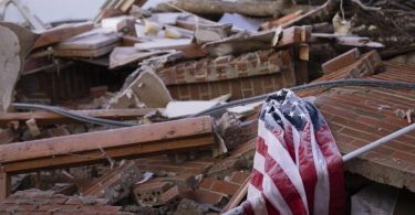 Die US-Flagge in den Trümmern eines von einem Tornado zerstörten Hauses im Bundesstaat Kentucky. Foto: Michael Clubb/AP/dpa