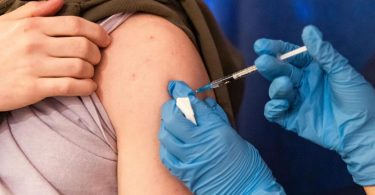 Einer Person wird der Corona-Impfstoff in den Oberarm verabreicht. Mit Omikron breitet sich eine Corona-Variante international aus, die Experten zufolge einen deutlich reduzierten Impfschutz erwarten lässt. Foto: Michael Matthey/dpa