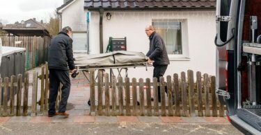 Bestatter bringen eine Trage mit einem Leichnam aus dem Wohnhaus in Glinde. Foto: Markus Scholz/dpa