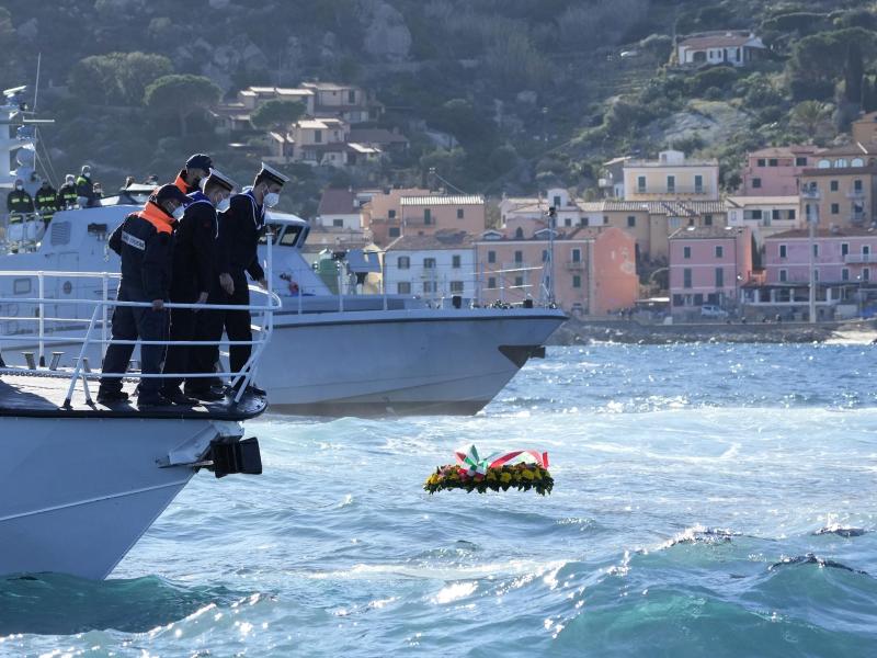 Matrosen lassen einen Blumenkranz zum Gedenken an die Opfer des Schiffsunglücks vor der Insel Giglio ins Meer. Foto: Andrew Medichini/AP/dpa