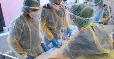 Pfleger und Pflegerinnen sowie eine Ärztin kümmern sich auf der Intensivstation für Corona-Patienten um einen Patienten. Foto: Sebastian Gollnow/dpa