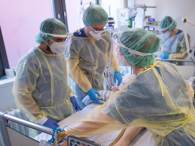 Pfleger und Pflegerinnen sowie eine Ärztin kümmern sich auf der Intensivstation für Corona-Patienten um einen Patienten. Foto: Sebastian Gollnow/dpa